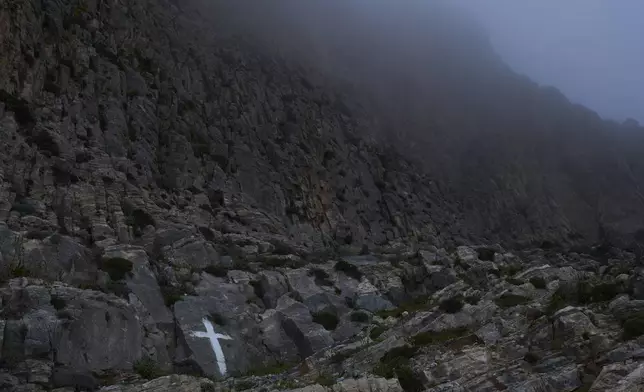 A cross is painted on a cliff near the Monastery of Panagia Hozoviotissa in Amorgos island, Greece, on Friday, March 28, 2025. (AP Photo/Petros Giannakouris)