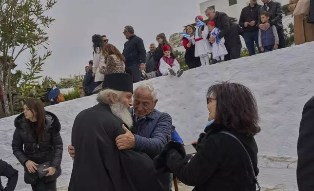 Orthodox Christian monk Father Spyridon is hugged by islanders as people gather to watch a parade for Greek Independence Day, which commemorates the start of the Greek War of Independence in 1821, in Amorgos island, Greece, on Tuesday, March 25, 2025. (AP Photo/Petros Giannakouris)