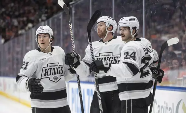 Los Angeles Kings' Jordan Spence (21), Vladislav Gavrikov (84) and Phillip Danault (24) celebrate after a goal against the Edmonton Oilers during first-period NHL hockey game action in Edmonton, Alberta, Monday, April 14, 2025. (Jason Franson/The Canadian Press via AP)