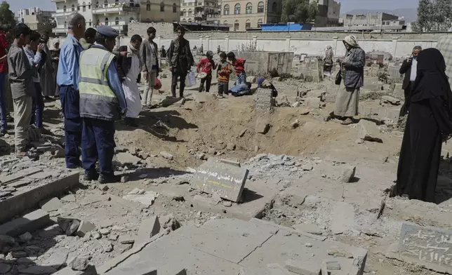 Yemenis watch a crater of a explosion at Magel Al-Dammah cemetery a day after it was hit by U.S. airstrikes in Sanaa, Yemen, Sunday, April 20, 2025. (AP Photo)