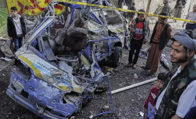 Yemenis watch a damaged vehicle at Farwah popular market which Houthis said it was struck by U.S. airstrikes in Sanaa, Yemen, Monday, April 21, 2025. (AP Photo)