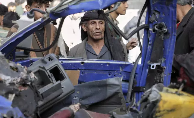 Yemenis watch a damaged vehicle at Farwah popular market, which Houthis said it was struck by U.S. airstrikes in Sanaa, Yemen, Monday, April 21, 2025. (AP Photo)