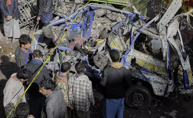 Yemenis watch a damaged vehicle at Farwah popular market which Houthis said it was struck by U.S. airstrikes in Sanaa, Yemen, Monday, April 21, 2025. (AP Photo