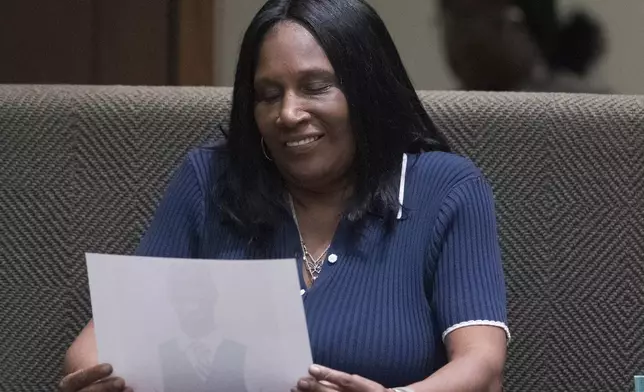 RowVaughn Wells, the mother of Tyre Nichols, smiles as she looks down at a photo of her son that is being submitted as evidence while she takes the stand as a witness during the first day of the criminal trial for the death of Nichols in Memphis, Tenn., on Monday, April 28, 2025. (Chris Day/Commercial Appeal/USA Today Network, via AP, Pool)