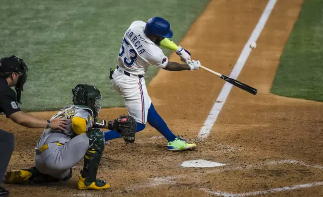 Texas Rangers Adolis García, right, bats against the Athletics during the seventh inning of a baseball game Monday, April 28, 2025, in Arlington, Texas. (AP Photo/Jessica Tobias)