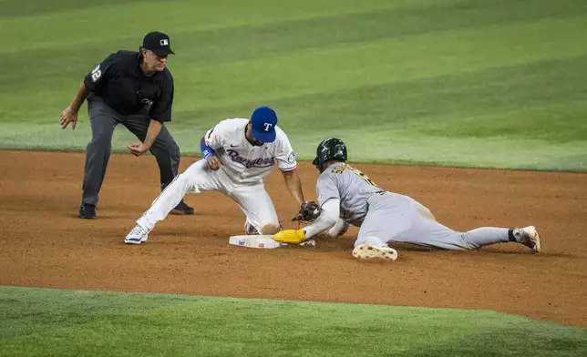 Texas Rangers' Marcus Semien, center, tags out Athletics' Max Schuemann at second base during the seventh inning of a baseball game Monday, April 28, 2025, in Arlington, Texas. (AP Photo/Jessica Tobias)