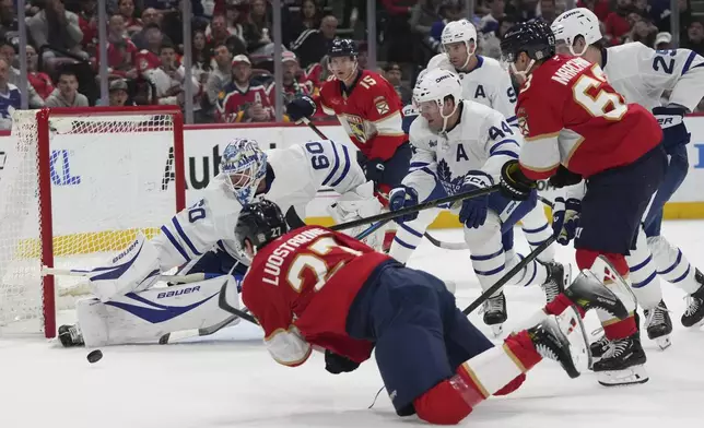 Florida Panthers center Eetu Luostarinen (27) falls to the ice as he attempts a shot on a goal against Toronto Maple Leafs goaltender Joseph Woll (60) during the second period of an NHL hockey game, Tuesday, April 8, 2025, in Sunrise, Fla. (AP Photo/Lynne Sladky)