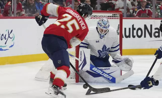 Florida Panthers right wing Mackie Samoskevich (25) attempts a shot on the goal as Toronto Maple Leafs goaltender Joseph Woll, right, defends during the second period of an NHL hockey game, Tuesday, April 8, 2025, in Sunrise, Fla. (AP Photo/Lynne Sladky)