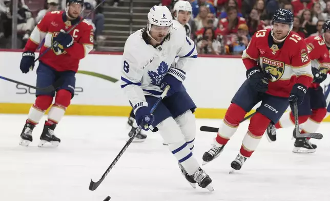Toronto Maple Leafs defenseman Chris Tanev (8) skates with he puck as Florida Panthers center Sam Reinhart (13) defends during the second period of an NHL hockey game, Tuesday, April 8, 2025, in Sunrise, Fla. (AP Photo/Lynne Sladky)