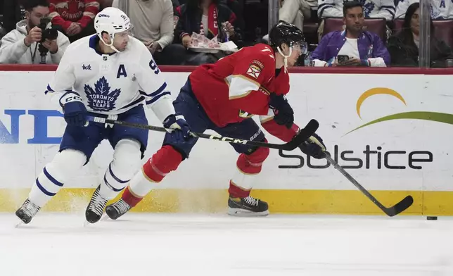 Toronto Maple Leafs center John Tavares (91) and Florida Panthers defenseman Niko Mikkola (77) go for the puck during the first period of an NHL hockey game, Tuesday, April 8, 2025, in Sunrise, Fla. (AP Photo/Lynne Sladky)