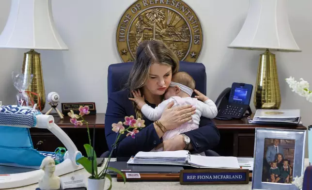 Florida Rep. Fiona McFarland, R-Sarasota, holds her 7-month-old daughter Grace Melton while working at her desk, Thursday, April 17, 2025, in Tallahassee, Fla. (AP Photo/Colin Hackley)