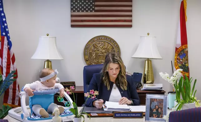 Florida Rep. Fiona McFarland, R-Sarasota, reviews a bill before committee as her 7-month-old daughter Grace Melton, left, watches, Thursday, April 17, 2025, in Tallahassee, Fla. (AP Photo/Colin Hackley)