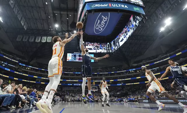 Atlanta Hawks guard Trae Young (11) shoots against a leaping Dallas Mavericks forward Caleb Martin (16) during the first half of an NBA basketball game in Dallas, Wednesday, April 2, 2025. (AP Photo/LM Otero)