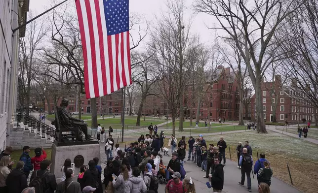 Visitors stop at the statue of John Harvard in Harvard Yard at Harvard University, Tuesday, April 15, 2025, in Cambridge, Mass. (AP Photo/Charles Krupa)