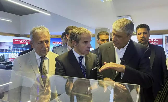 In this photo released by the Atomic Energy Organization of Iran, International Atomic Energy Agency (IAEA) Director General, Rafael Mariano Grossi, center, listens to head of the Atomic Energy Organization of Iran Mohammad Eslami as he visits an exhibition of Iran's nuclear achievements, in Tehran, Iran, Thursday, April 17, 2025. (Atomic Energy Organization of Iran via AP)