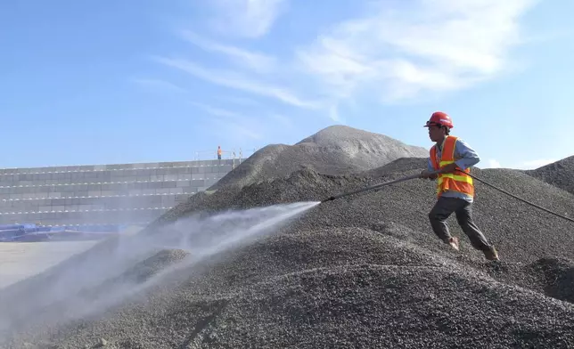 FILE- A Vietnamese worker sprays water over stones to be used in the construction of a silo for storing soil contaminated with Agent Orange dioxide at the site of a former American airbase in Danang, Vietnam on Wednesday, April 24, 2013. (AP Photo/Hau Dinh, File)