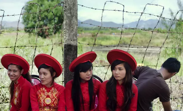 FILE- Attendants sit next to a field contaminated with dioxin before a ceremony marking the start of a project to clean up dioxin left over from the Vietnam War, at a former U.S. military base in Danang, Vietnam Thursday Aug. 9, 2012. (AP Photo/Maika Elan, File)