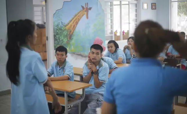 Truong Minh Phu, 20, centre, sits in a classroom with other students at a school for victims of Agent Orange in Da Nang, Vietnam, March 7, 2025. (AP Photo/Aniruddha Ghosal)