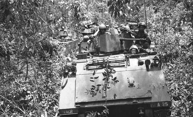 FILE- Armored personnel carriers with tank support move through dense underbrush with a payload of South Vietnamese infantrymen and U.S. cavalrymen during patrol through jungle 40 miles northeast of Saigon on June 5, 1969. (AP Photo/Rick Merron, File)