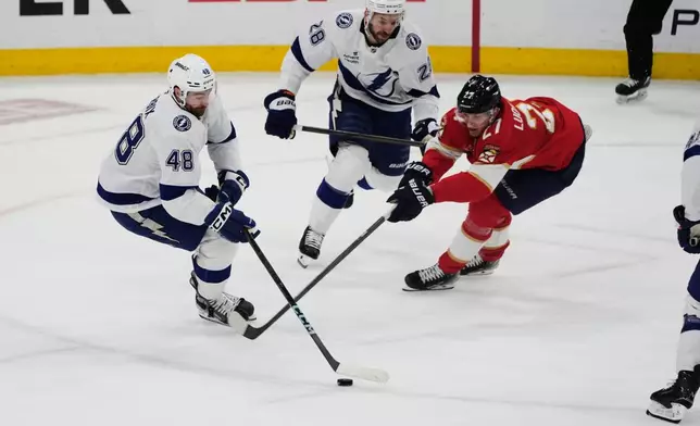 Florida Panthers center Eetu Luostarinen (27) and Tampa Bay Lightning defenseman Nick Perbix (48) go after the puck during the first period in Game 4 of an NHL hockey Stanley Cup first-round playoff series, Monday, April 28, 2025, in Sunrise, Fla. (AP Photo/Marta Lavandier)