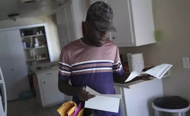 Haitian immigrants Kevenson Jean, a truck driver, looks over papers at his home, Monday, April 14, 2025, in Panhandle, Texas. (AP Photo/Eric Gay)