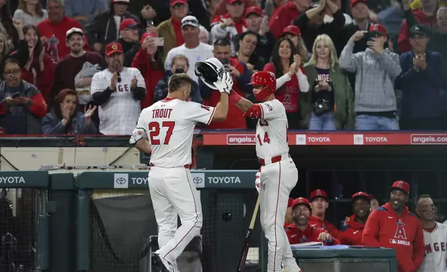 Los Angeles Angels' Logan O'Hoppe (14) places a helmet on Mike Trout (27) after Trout hit a home run during the sixth inning of a baseball game against the San Francisco Giants in Anaheim, Calif., Saturday, April 19, 2025. (AP Photo/Jessie Alcheh)