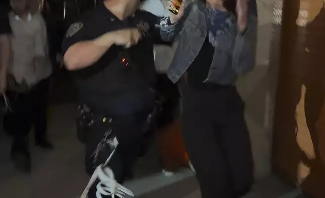 This image taken from video shows a woman and a police officer as they are pursued by a crowd of men in the Crown Heights section of Brooklyn, N.Y., on Thursday, April 24, 2025. (AP Photo)