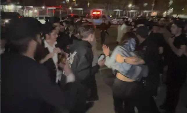 This image taken from video shows a woman and a police officer as they are pursued by a crowd of men in the Crown Heights section of Brooklyn, N.Y., on Thursday, April 24, 2025. (AP Photo)