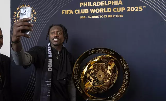Philadelphia Eagles NFL football player A.J. Brown takes a selfie as he poses with the trophy at a welcoming event for the 2025 FIFA Club World Cup soccer tournament, Thursday, April 10, 2025, in Philadelphia. (AP Photo/Chris Szagola)