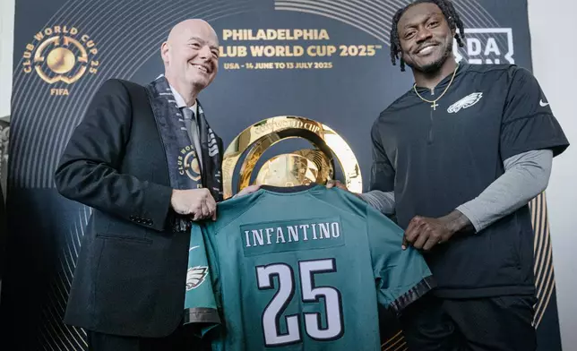 FIFA President Gianni Infantino, left, and Philadelphia Eagles NFL football player A.J. Brown, left, pose with an Eagles jersey during a welcoming event for the 2025 FIFA Club World Cup soccer tournament, Thursday, April 10, 2025, in Philadelphia. (Jose F. Moreno/The Philadelphia Inquirer via AP)