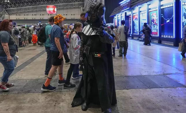 A Star Wars fan dressed as Darth Vader tries to demonstrate the Force during a fan convention called the Star Wars Celebration Japan in Chiba, near Tokyo, Friday, April 18, 2025. (AP Photo/Hiro Komae)