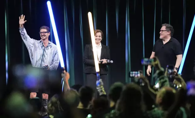 From left, actors Pedro Pascal and Sigourney Weaver react to audience members as director Jon Favreau looks on during a fan convention called the Star Wars Celebration Japan in Chiba, near Tokyo, Friday, April 18, 2025. (AP Photo/Hiro Komae)