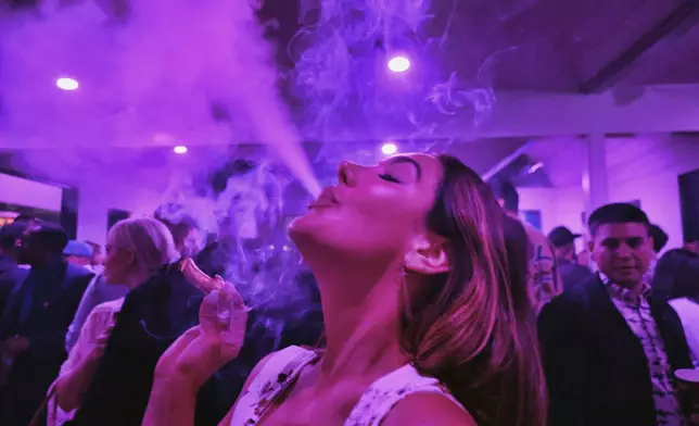 FILE - A guest takes a puff from a marijuana cigarette at the Sensi Magazine party celebrating the 420 holiday in the Bel Air section of Los Angeles, April 20, 2019. (AP Photo/Richard Vogel, File)