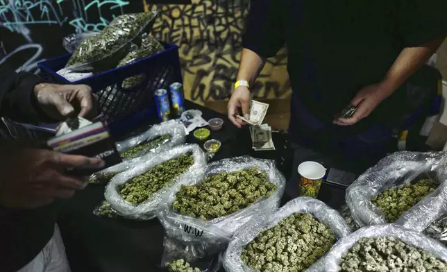 FILE - A vendor makes change for a marijuana customer at a cannabis marketplace in Los Angeles, April 15, 2019. (AP Photo/Richard Vogel, File)