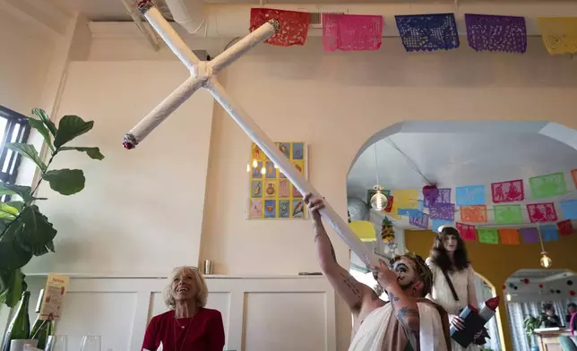 Drag performer Ed Du'Bull holds a cross made to look like lit joints and pretends smoke from it while performing during a "blaze and praise" drag brunch at Bar Carlo on Sunday, April 20, 2025, in Portland, Ore. (AP Photo/Jenny Kane)
