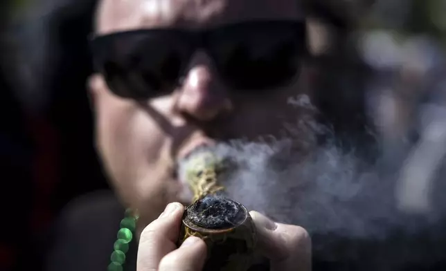 Robert Borst smokes marijuana in a pipe on Hippie Hill where a Volo Sports, "Peace, Love and Volo Sports" event that coincided with Easter gatherings, and an unofficial 420 gathering at Robin Williams Meadow in Golden Gate Park in San Fr, on Sunday, April 20, 2025. (Carlos Avila Gonzalez/San Francisco Chronicle via AP)
