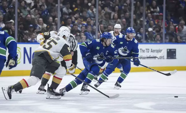 Vancouver Canucks' Quinn Hughes, right, vies for the puck against Vegas Golden Knights' Keegan Kolesar (55) and Jonas Rondbjerg, back left, during the second period of an NHL hockey game, in Vancouver, on Wednesday, April 16, 2025. (Darryl Dyck/The Canadian Press via AP)