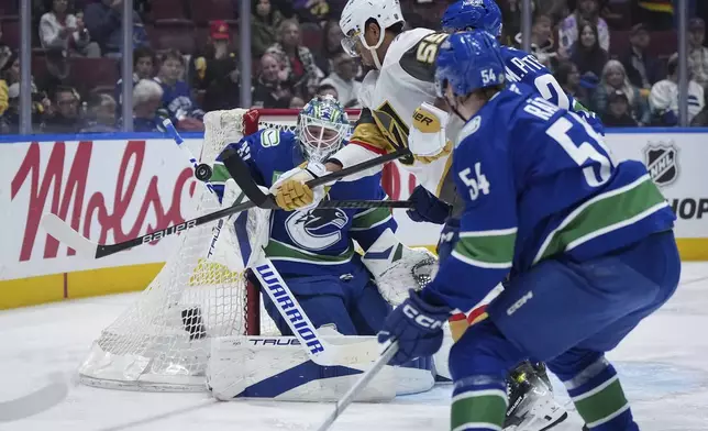 Vancouver Canucks goalie Kevin Lankinen, back, makes the save as Vegas Golden Knights' Keegan Kolesar (55) vies for the rebound against Vancouver's Marcus Pettersson, back right, during the second period of an NHL hockey game in Vancouver, on Wednesday, April 16, 2025. (Darryl Dyck/The Canadian Press via AP)