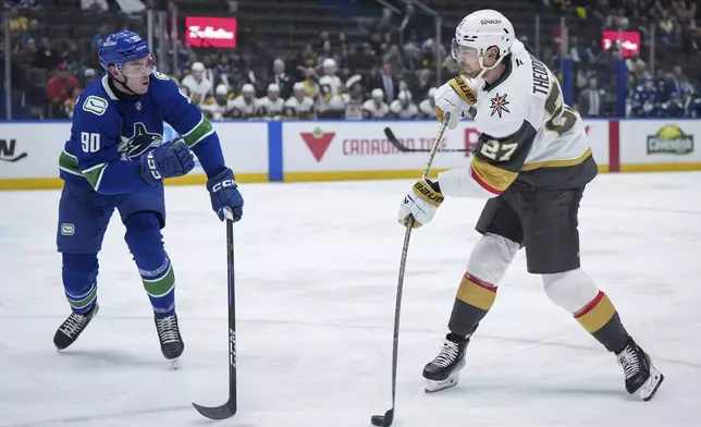 Vegas Golden Knights' Shea Theodore (27) takes a shot on goal as Vancouver Canucks' Vittorio Mancini (90) defends during the second period of an NHL hockey game in Vancouver, on Wednesday, April 16, 2025. (Darryl Dyck/The Canadian Press via AP)