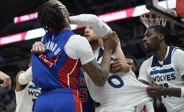 Detroit Pistons forward Ronald Holland II (00) left, and Minnesota Timberwolves guard Donte DiVincenzo, middle, fight during the first half of an NBA basketball game, Sunday, March 30, 2025, in Minneapolis. (AP Photo/Abbie Parr)