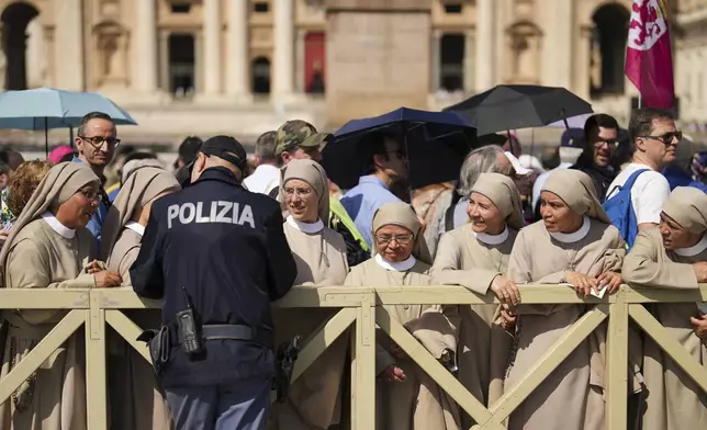 Nuns arriving from Spain, some from South America, chat with a policeman while waiting in line to see the body of Pope Francis, who will lie in state for three days, in St. Peter's Basilica at the Vatican, Wednesday, April 23, 2025. (AP Photo/Francisco Seco)