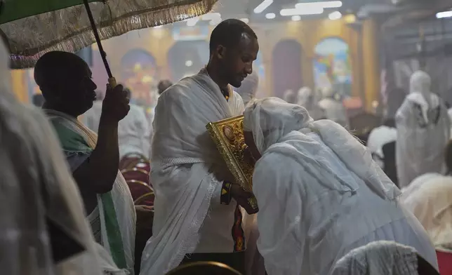 Worshippers kiss the holy Gospel during service at Re'ese Adbarat Debre Selam Kidist Mariam Church, an Ethiopian Orthodox Tewahedo church, in Washington, D.C., Saturday, April 5, 2025. (AP Photo/Jessie Wardarski)