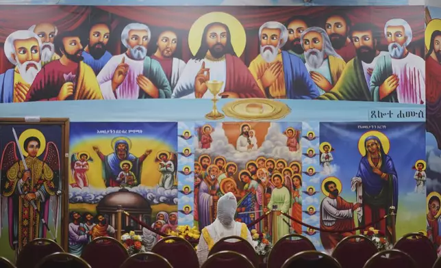 A worshipper kneels before a depiction of "The Last Supper" at Re'ese Adbarat Debre Selam Kidist Mariam Church, an Ethiopian Orthodox Tewahedo church, in Washington, D.C., Saturday, April 5, 2025. (AP Photo/Jessie Wardarski)