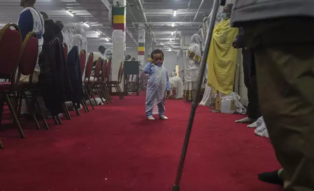 A young child wears a netela, the white scarf-like cotton cloth worn by worshippers, during a service at Re'ese Adbarat Debre Selam Kidist Mariam Church, an Ethiopian Orthodox Tewahedo church, in Washington, D.C., Saturday, April 5, 2025. (AP Photo/Jessie Wardarski)