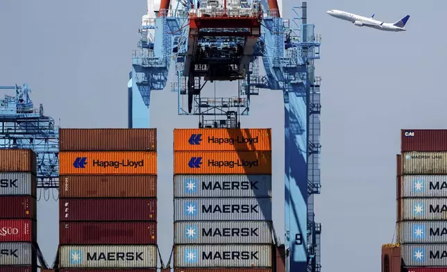 An airplane flies over the container ship Alexandra at the Port Newark Container Terminal, Friday, April 18, 2025, in Newark, N.J. (AP Photo/Julia Demaree Nikhinson)