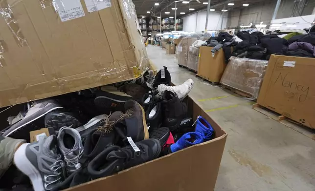 Boxes of returned or overstocked clothing, shoes, boots, coats, packs and other items sit in a warehouse where the goods are cleaned or repaired before they are marketed on resale platforms Thursday, April 17, 2025, in Englewood, Colo. (AP Photo/David Zalubowski)
