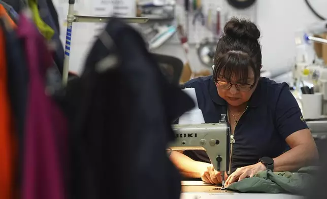 A worker sews a coat in a warehouse where the goods from various clothing manufacturers are cleaned or repaired before they are marketed on resale platforms Thursday, April 17, 2025, in Englewood, Colo. (AP Photo/David Zalubowski)