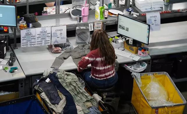 People work amid boxes of returned or overstocked clothing, shoes, boots, coats, packs and other items in a warehouse where the goods are cleaned or repaired before they are marketed on resale platforms in Englewood, Colo., on Thursday, April 17, 2025. (AP Photo/David Zalubowski)