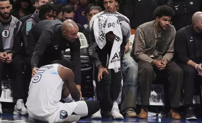 Brooklyn Nets head coach Jordi Fernandez, left, and D'Angelo Russell, right, check on Minnesota Timberwolves' Anthony Edwards, below, after he was injured during the first half of an NBA basketball game Thursday, April 3, 2025, in New York. (AP Photo/Frank Franklin II)