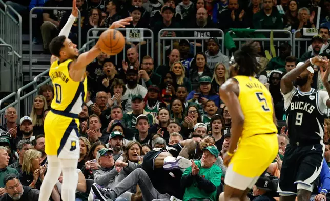 Milwaukee Bucks' Kevin Porter Jr. leaps into the crowd trying to save a ball against the Indiana Pacers during the first half of Game 4 of a first-round NBA basketball playoff series Sunday, April 27, 2025, in Milwaukee. (AP Photo/Jeffrey Phelps)